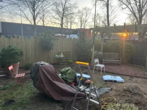 Chantier en cours avec panneaux bois, banc et plantes en pots à Buc