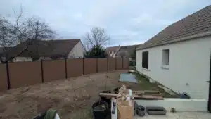 Clôture en panneaux bruns posée tout autour d’un jardin