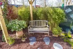 Banc en bois sous une pergola, pas japonais et plantations du coin zen à Buc