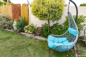 Fauteuil suspendu au milieu des massifs devant une palissade