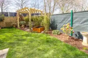 Gazon, massifs paillés et pergola au fond du jardin de Buc