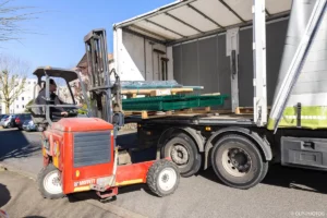 Livraison des matériaux par camion-grue avec un mini-dumper rouge à Buc