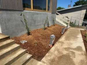 Massif paillé planté d’arbustes le long des marches de la cantine de Guerville