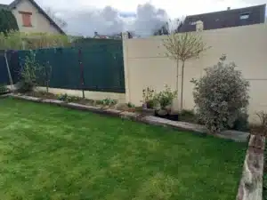 Massifs plantés le long d’une palissade et d’un mur clair