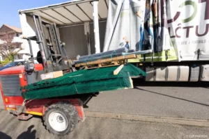 Mini-dumper chargé de panneaux déchargé d’un camion à Buc