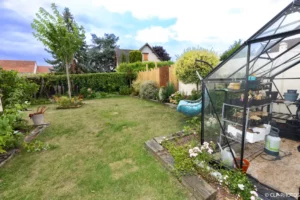 Pelouse, serre et arbres au fond du jardin