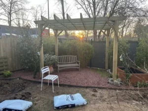 Pergola en bois installée et massifs en préparation dans le jardin de Buc
