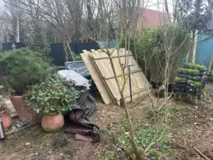 Plantes en pots et panneaux en bois en attente de pose dans le jardin de Buc
