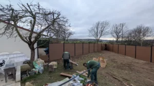 Jardiniers posant une clôture en panneaux après l’arrachage de la haie
