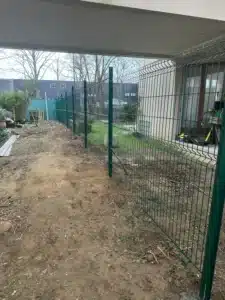Sol préparé le long du grillage rigide avant plantation à Buc