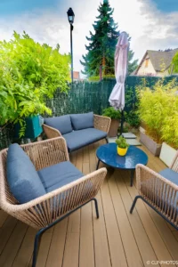 Salon de jardin sur une terrasse en bois entourée de plantes