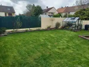 Vue d’ensemble du jardin avec serre, pelouse et massifs